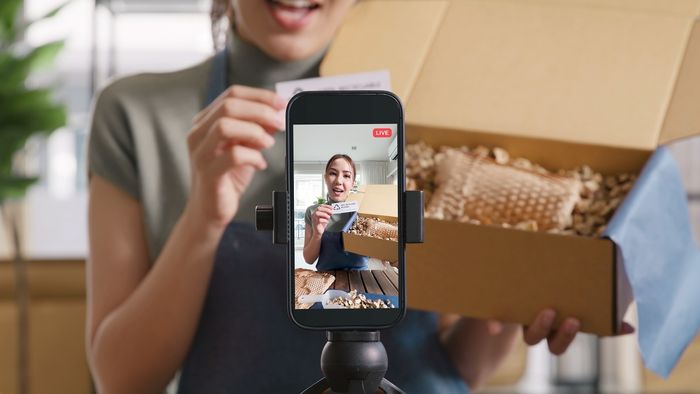 a woman filming herself packing an order into a box preview image